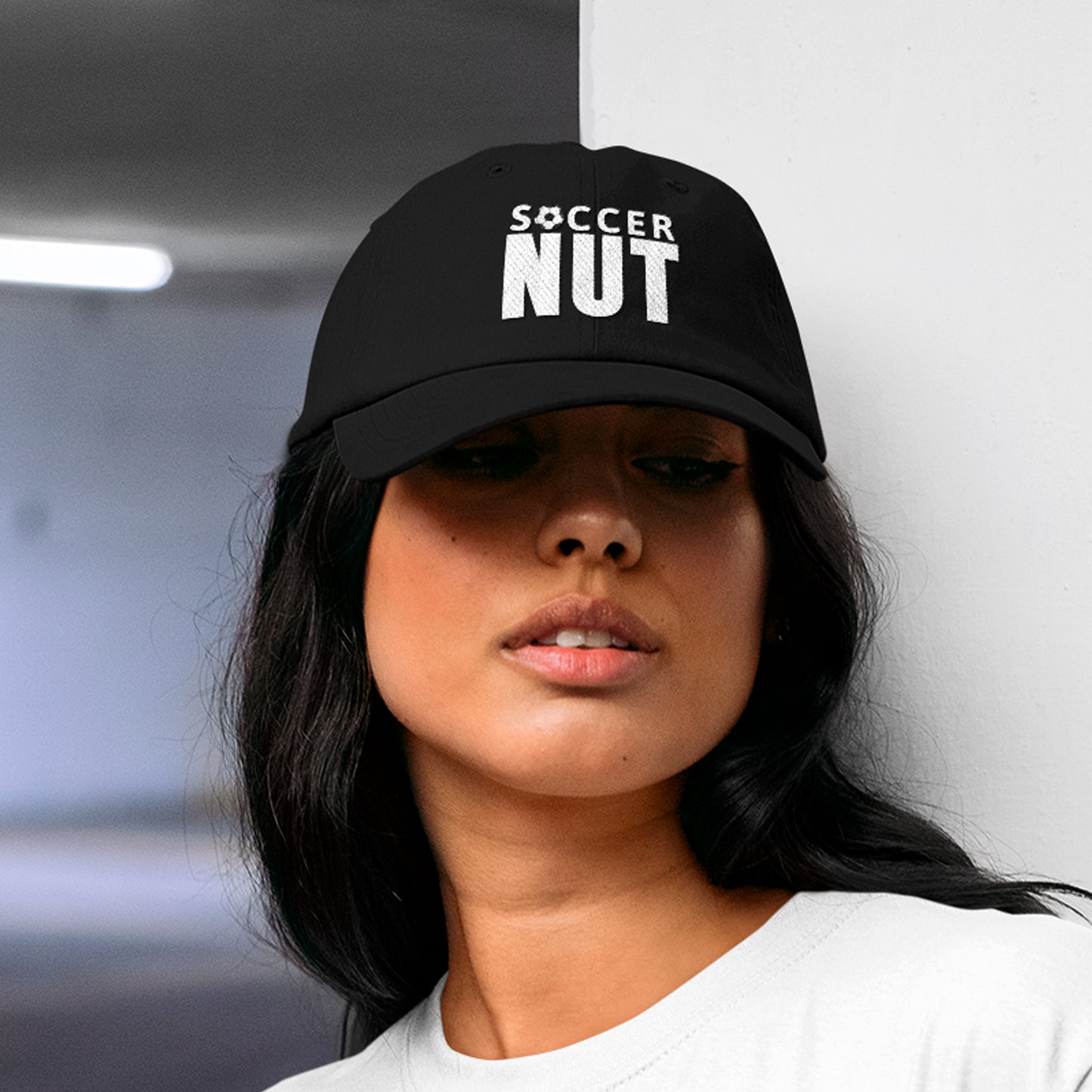 Soccer Mom wearing a black 'SOCCER NUT' cap at her son's game